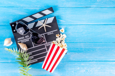Summer holiday and vacation movie cinema marathon background Cinema clapper-board with sunglasses, seashells, starfish, popcorn buckets, vacation accessories, Cinema for the summer Movie Night partyの写真素材