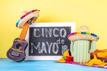 Cinco de Mayo holiday background with Mexican cactus decor, party sombrero hat, nachos chips, guitar, maracas. Cinco de Mayo holiday celebration greeting card, copy spaceの写真素材
