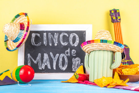 Cinco de Mayo holiday background with Mexican cactus decor, party sombrero hat, nachos chips, guitar, maracas. Cinco de Mayo holiday celebration greeting card, copy spaceの写真素材