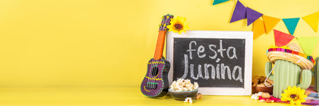 Festa Junina Brazil holiday greeting card background. Summer Brazilian harvest festival party background with traditional food - popcorn, peanuts, holiday hat, guitar, copy spaceの写真素材