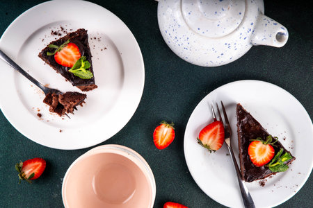 Dark chocolate cake slices, with chocolate cream and strawberry, on portioned plates, copy spaceの写真素材
