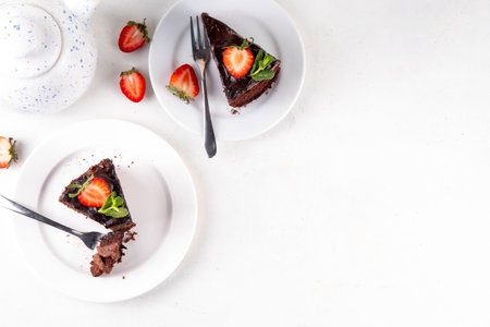 Dark chocolate cake slices, with chocolate cream and strawberry, on portioned plates, copy spaceの写真素材