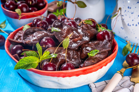 Sweet dessert chocolate dumplings vareniki with cherry berries and chocolate sauce, with sugar powder. Traditional ukrainian, polish, east european pierogi dumplingsの写真素材