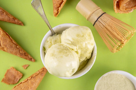 Matcha ice cream. Bowl with matcha green tea taste gellato with ice cream waffle cones. Vegan non-dairy summer dessert with matcha latte powder on topの写真素材