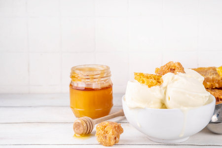 Custard base Milk and honey ice cream, sweet summer frozen dessert, bowl of creamy homemade honey taste gelato with honeycomb topping and honey drizzlesの写真素材
