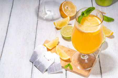 Trendy Tea Inspired cocktail set from green, oolong, black, chai and other tea blends. Sparkling tea soda, cold summer drinks with syrup, lemon, lime and mint, on sun lighted white wooden backgroundの写真素材