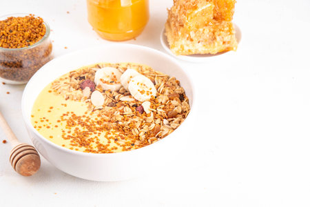 Healthy superfood fruit smoothie bowl with bee pollen, golden creamy shake or smoothie, with granola and banana. Clean eating, dieting vegetarian dish with bee pollen superfood organic powderの写真素材