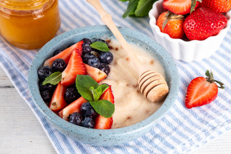 Cream of Wheat semolina porridge with fresh summer berry. Portion of breakfast whole grain creme de  semolina with dairy milk, strawberry, blueberry and honeyの写真素材