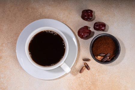 Healthy organic date seed coffee, black coffee cup, made with grated date seeds, with whole date fruits and seeds on beige background . Alternative coffee hot drinkの写真素材