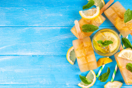 Iced tea or lemonade popsicles, sweet lemon and mint cocktail lollies with cold drink, lemon slices and mint leaves copy spaceの写真素材