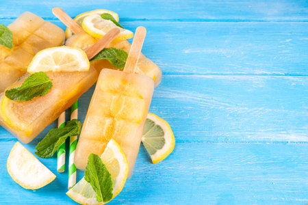 Iced tea or lemonade popsicles, sweet lemon and mint cocktail lollies with cold drink, lemon slices and mint leaves copy spaceの写真素材