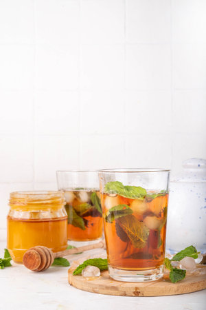 Mint and honey iced tea drink, cold summer refreshment cold beverage with a lot of mint leaves, honey and iced cubes, copy spaceの写真素材