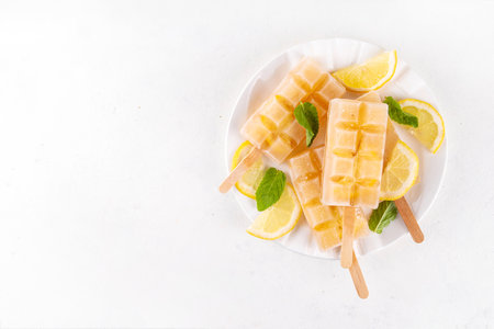 Iced tea or lemonade popsicles, sweet lemon and mint cocktail lollies with cold drink, lemon slices and mint leaves copy spaceの写真素材