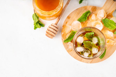 Mint and honey iced tea drink, cold summer refreshment cold beverage with a lot of mint leaves, honey and iced cubes, copy spaceの写真素材