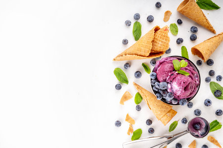 Blueberry rich creamy sorbet, tasty blueberry fruit ice cream with fresh berries, mint leaves and ice cream waffle cones on white table copy spaceの写真素材