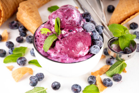 Blueberry rich creamy sorbet, tasty blueberry fruit ice cream with fresh berries, mint leaves and ice cream waffle cones on white table copy spaceの写真素材