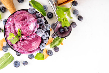 Blueberry rich creamy sorbet, tasty blueberry fruit ice cream with fresh berries, mint leaves and ice cream waffle cones on white table copy spaceの写真素材
