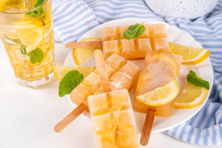 Iced tea or lemonade popsicles, sweet lemon and mint cocktail lollies with cold drink, lemon slices and mint leaves copy spaceの写真素材