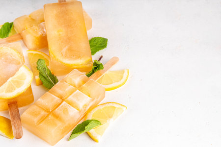 Iced tea or lemonade popsicles, sweet lemon and mint cocktail lollies with cold drink, lemon slices and mint leaves copy spaceの写真素材