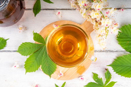 Organic natural chestnut leaves and flower tea. Hot alternative non-caffeine herbal drink, tasty healthy beverage, on white wooden background copy spaceの写真素材