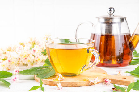 Organic natural chestnut leaves and flower tea. Hot alternative non-caffeine herbal drink, tasty healthy beverage, on white wooden background copy spaceの写真素材