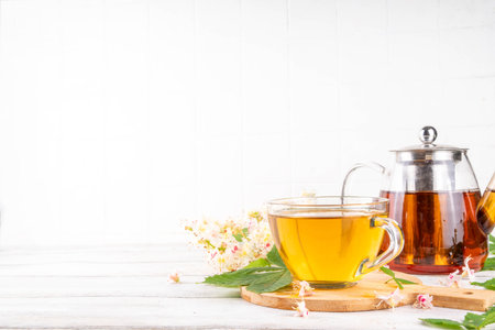 Organic natural chestnut leaves and flower tea. Hot alternative non-caffeine herbal drink, tasty healthy beverage, on white wooden background copy spaceの写真素材