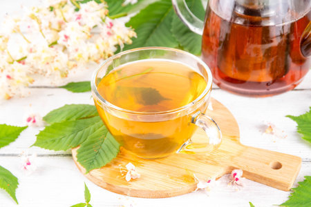 Organic natural chestnut leaves and flower tea. Hot alternative non-caffeine herbal drink, tasty healthy beverage, on white wooden background copy spaceの写真素材