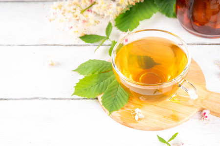 Organic natural chestnut leaves and flower tea. Hot alternative non-caffeine herbal drink, tasty healthy beverage, on white wooden background copy spaceの写真素材