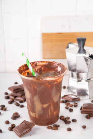 Viral Cracking Chocolate Latte drink. Plastic glass with cracked milk chocolate layer poured with iced latte, sweet coffee moccachino beverageの写真素材