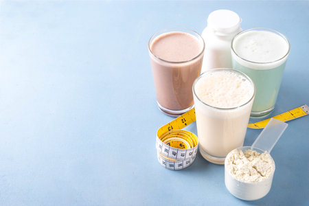 Assortment of different flavors of protein cocktails, with protein powder scoop, measuring tape. Protein shakes for weight loss, set every day protein goals, sport and fitness, healthy lifestyleの写真素材