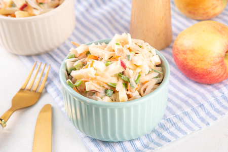 Asian Apple Slaw Salad with Apples, cabbage, carrot and spring onions. Healthy fall vegetable salad with yogurt dressing, in portioned bowls on kitchen tableの写真素材