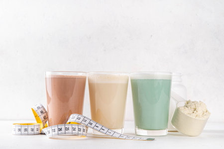 Assortment of different flavors of protein cocktails, with protein powder scoop, measuring tape. Protein shakes for weight loss, set every day protein goals, sport and fitness, healthy lifestyleの写真素材