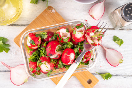 Smashed radish salad. Marinated spring radishes with soy sauce, parsley, garlic, olive oil and dill. Healthy vegan dish, creative vegetable salad idea, on white wooden tableの写真素材
