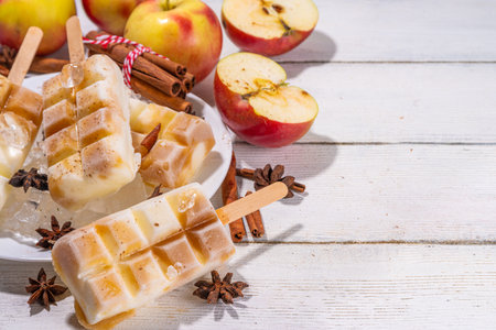 Apple pie ice cream popsicles on a stick. Homemade lollipops with apple pie flavor, on wooden table backgroundの写真素材