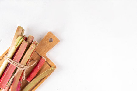Raw fresh organic rhubarb stems on kitchen table background, bunch of homegrown pink and green rhubarb ready for cooking, on cutting board. Summer harvest, summer food and dessert cooking ingredientの写真素材