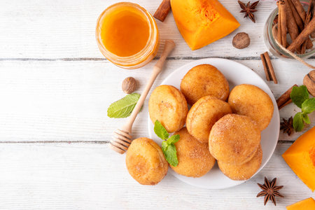 Autumn pumpkin pie donuts with cinnamon sugar sprinkled topping and pumpkin spice filling, on white wooden table with honey and pumpkin squash slices, copy spaceの写真素材