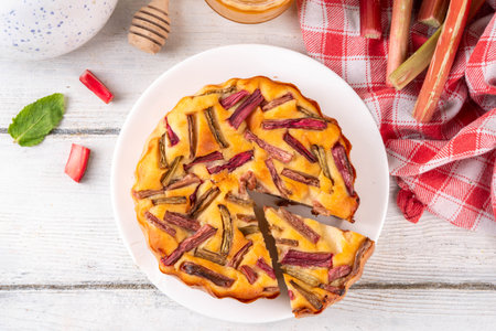 Summer homemade baking, tasty rhubarb pie. Sweet seasonal dessert recipe, sponge cake with rhubarb slices on top and sweet jam insideの写真素材