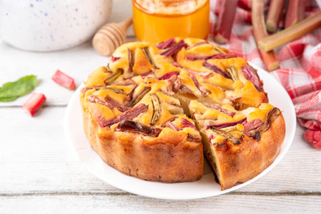 Summer homemade baking, tasty rhubarb pie. Sweet seasonal dessert recipe, sponge cake with rhubarb slices on top and sweet jam insideの写真素材