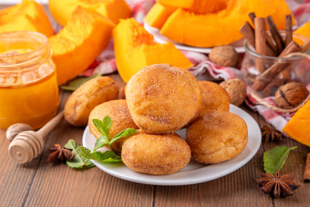 Autumn pumpkin pie donuts with cinnamon sugar sprinkled topping and pumpkin spice filling, on white wooden table with honey and pumpkin squash slices, copy spaceの写真素材