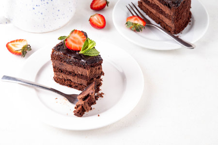 Dark chocolate cake slices, with chocolate cream and strawberry, on portioned plates, copy spaceの写真素材