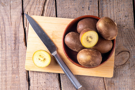 Sweet golden kiwi fruits, whole and sliced, on kitchen tableの写真素材