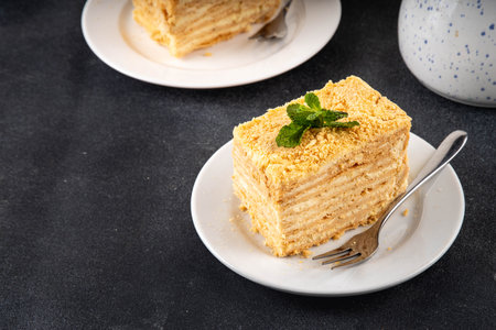 Homemade Napoleon cake slices, layered mille-feuille cake with vanilla creamy custard, tasty delicious puff pastry, on serving plates with forks, copy spaceの写真素材