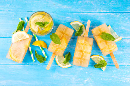 Iced tea or lemonade popsicles, sweet lemon and mint cocktail lollies with cold drink, lemon slices and mint leaves copy spaceの写真素材