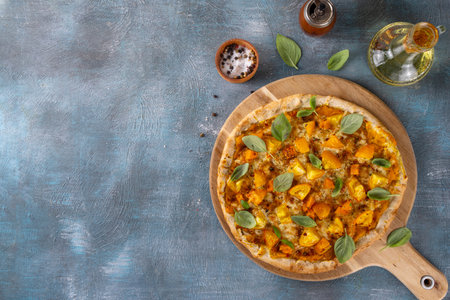 Homemade vegetarian vegetable pizza margarita with pumpkin sauce, pumpkin squash chunks and yellow tomatoes, autumn comfort warm food, copy spaceの写真素材
