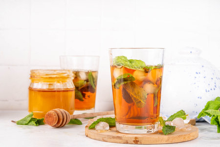 Mint and honey iced tea drink, cold summer refreshment cold beverage with a lot of mint leaves, honey and iced cubes, copy spaceの写真素材