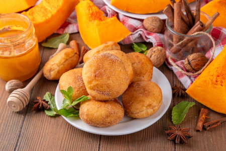 Autumn pumpkin pie donuts with cinnamon sugar sprinkled topping and pumpkin spice filling, on white wooden table with honey and pumpkin squash slices, copy spaceの写真素材