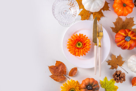 Autumn holiday table setting. Thanksgiving holiday menu, greeting card. White kitchen table with plate and cutlery, fall leaves, flowers and decor flat lay top view copy spaceの写真素材