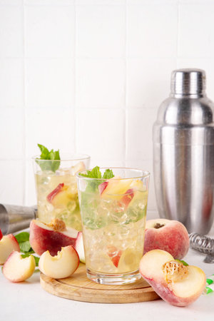 Flat peach lemonade, iced tea or mojito cocktail with fresh fruit garnish. Sweet non-alcohol flat chinese donuts fig peach mocktail with peach slices, mint and crushes iceの写真素材