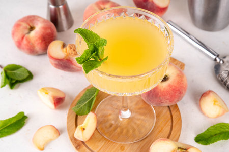 Flat peach martini or margarita lemonade cold fruit drink, summer iced fruit juice cocktail with mint and lemon, on white tableの写真素材