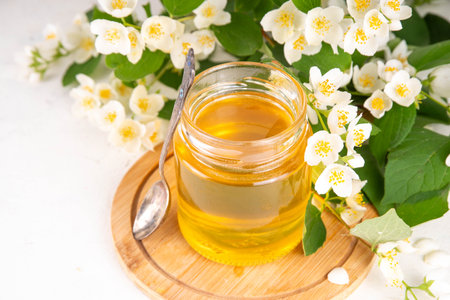 Homemade jasmine flower jam, floral golden confiture preserves with fresh jasmine flowers on white table backgroundの写真素材